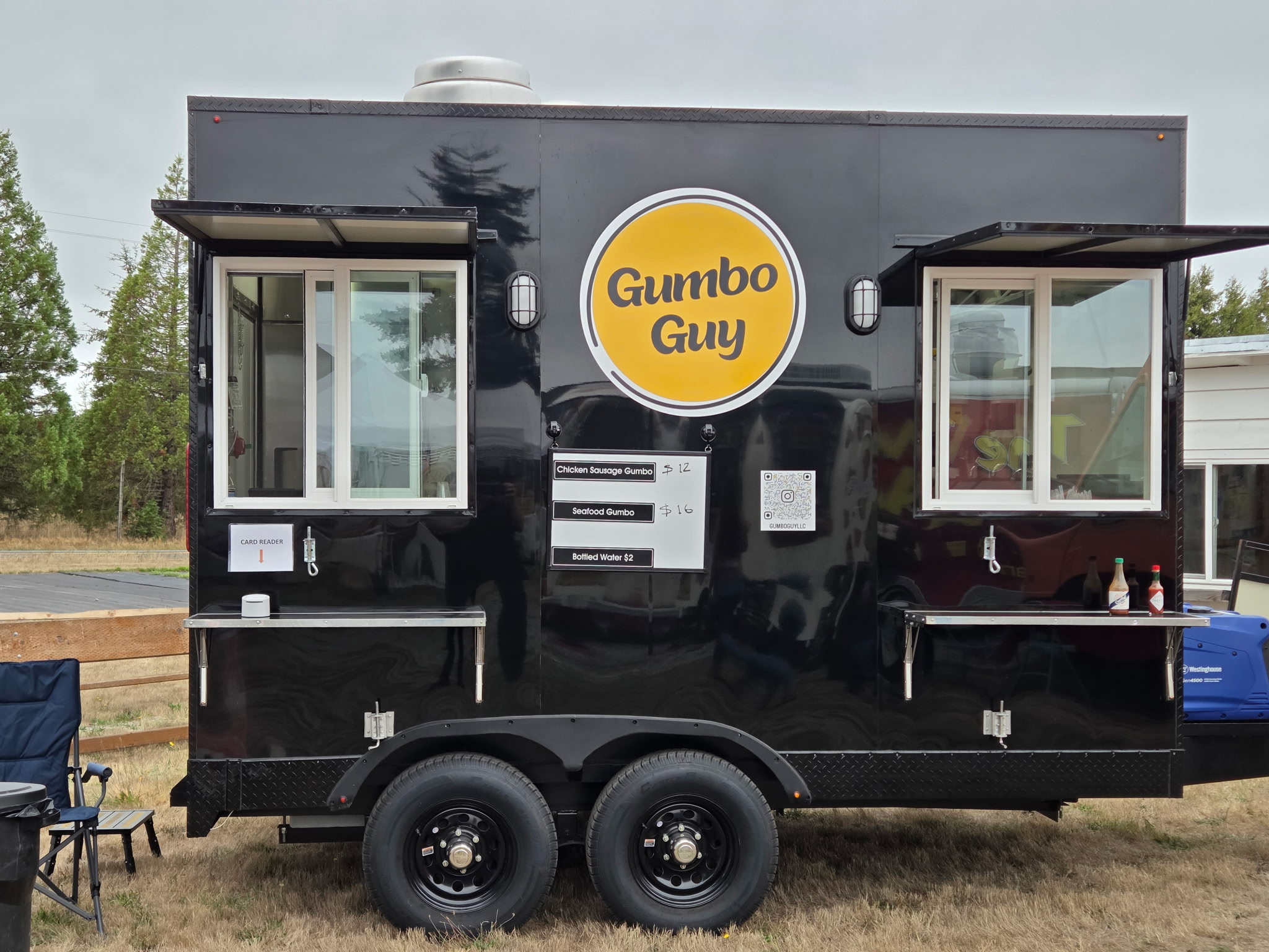 A straight-on view of the Gumbo Guy trailer with both serving windows and its yellow logo